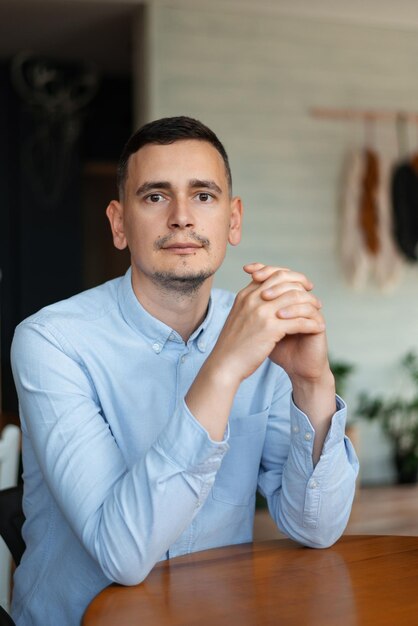 Photo portrait of a young man in a blue shirt in a cafe