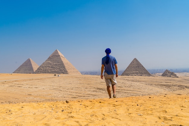 Photo portrait of a young man in a blue turban walking next to the pyramids of giza, cairo, egypt