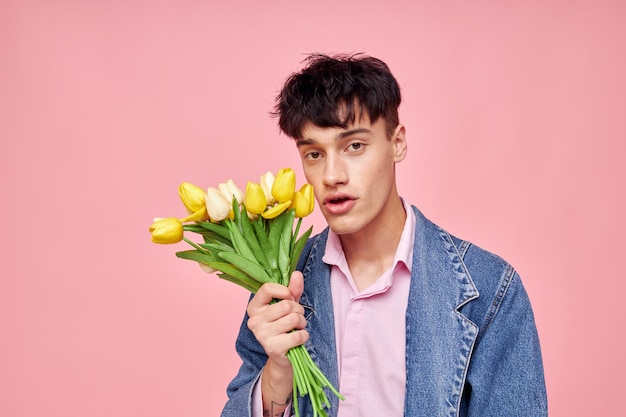 Portrait of a young man bouquet of yellow flowers gift holiday elegant style pink background unaltered