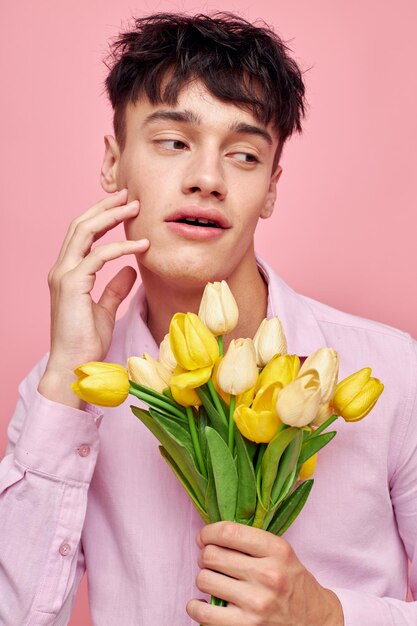 Portrait of a young man bouquet of yellow flowers romance posing fashion pink background unaltered