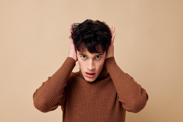 Portrait of a young man brown turtleneck posing fashion light\
background unaltered