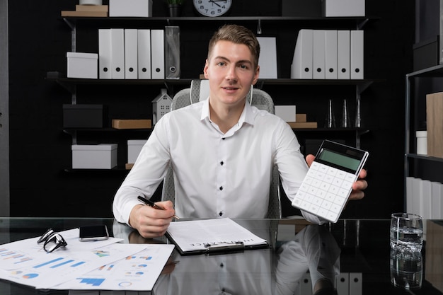 Portrait of young man in business space sitting at table in bright office