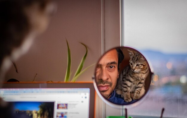 Photo portrait of young man and cat in a mirror at home