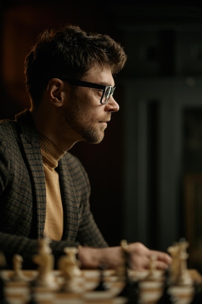 Portrait of young man chess player sitting at table with chessboard