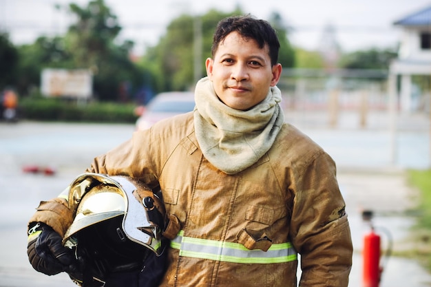 Portrait of young man firefighter standing near fire truck Fireman in protective suit with oxygen mask and helmet