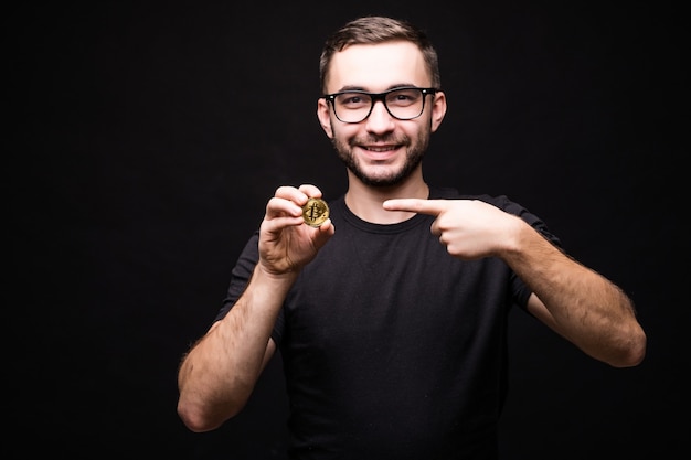 Portrait of young man in glasses wear in black shirt pointed on bitcoin isolated on black