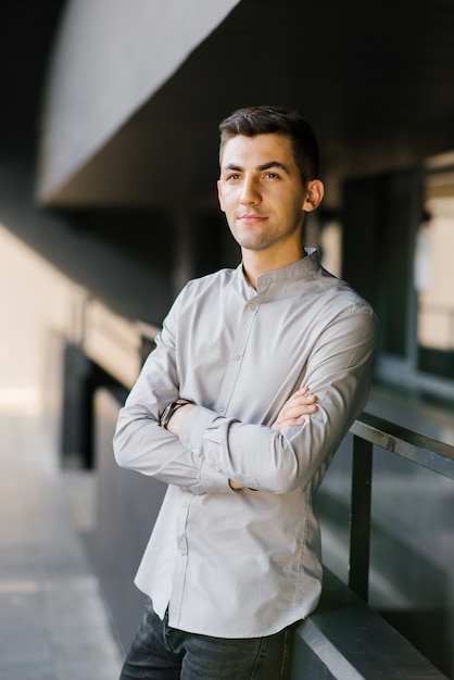 portrait of a young man or guy in a gray shirt, his arms folded across his chest