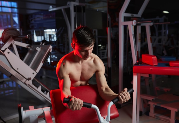 Portrait of a young man in the gym exercise for the biceps Lens flare