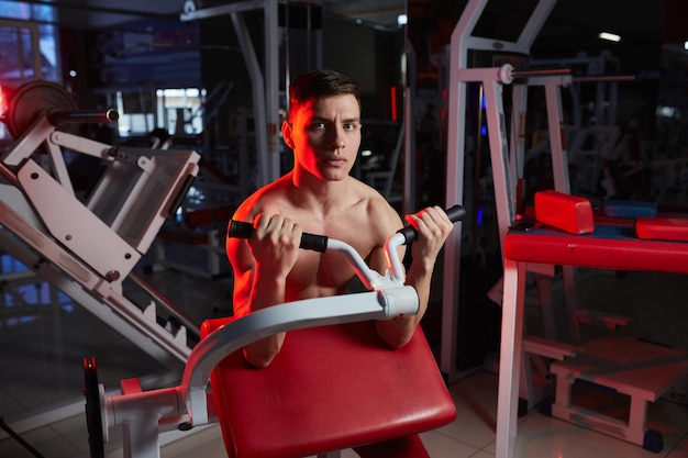 Portrait of a young man in the gym exercise for the biceps Lens flare