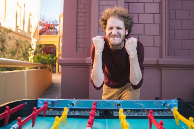 Photo portrait of young man having fun and playing table football