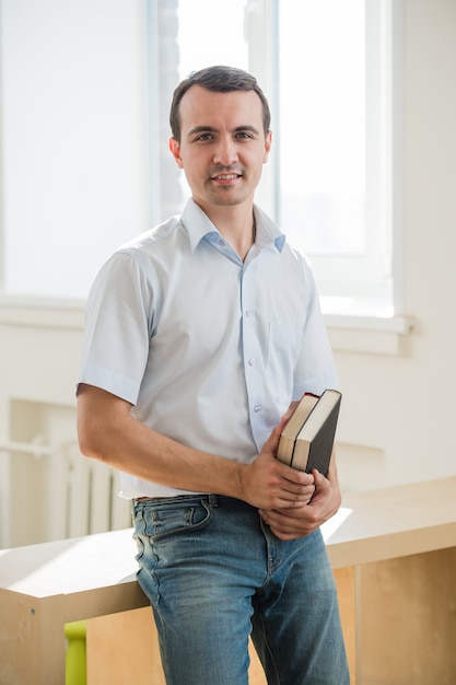 Portrait of young man holding books, looking