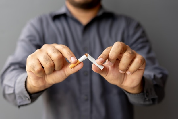 Portrait young man holding broken cigarette in hands happy male
quitting refusing smoking cigarettes quit bad habit stop smoking
cigarettes health care concept no smoking campaign