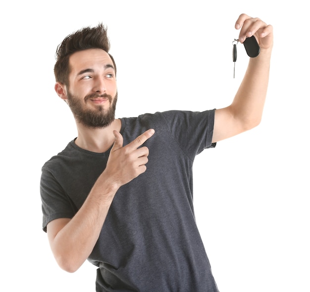 Portrait of young man holding car key, on white