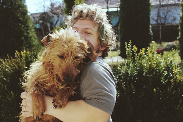 Photo portrait of young man holding dog at park during sunny day