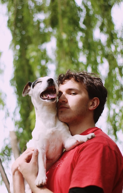 Foto ritratto di un giovane con un cane in mano