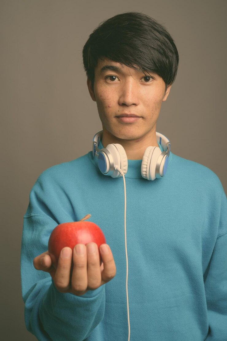 Photo 灰色背景下拿着眼镜的年轻人的肖像