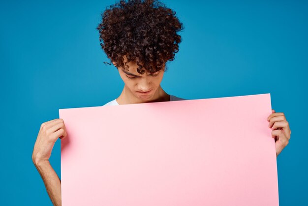 Portrait of young man holding paper against blue background