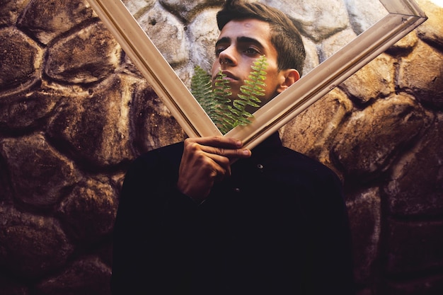 Portrait of young man holding picture frame