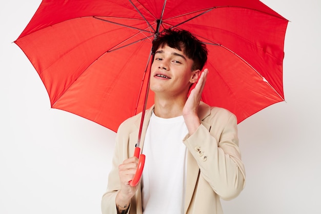 変更されていないファッションの明るい背景のポーズの手に傘を持っている若い男の肖像画