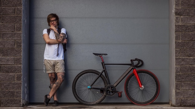 portrait of young man leaning against bicycle