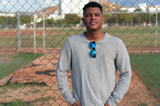 Portrait of a young man leaning against a fence