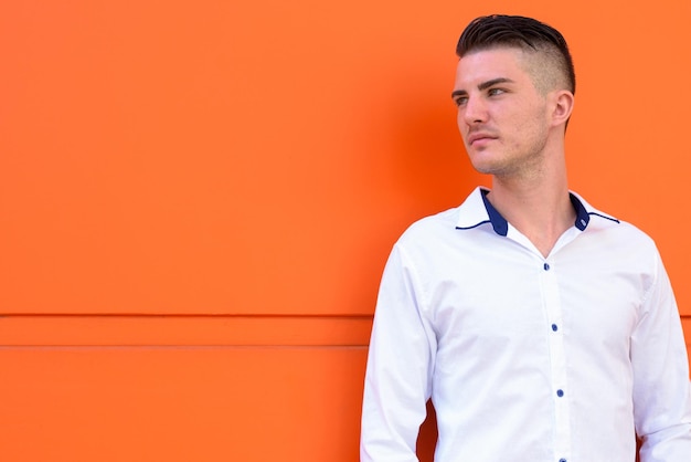 Photo portrait of young man looking away against orange wall