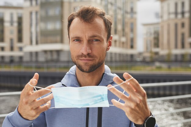 Portrait of young man looking at camera while wearing protective mask standing outdoors