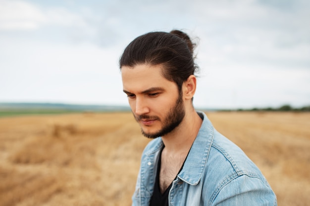 Portrait of young man looking down in wheat field.