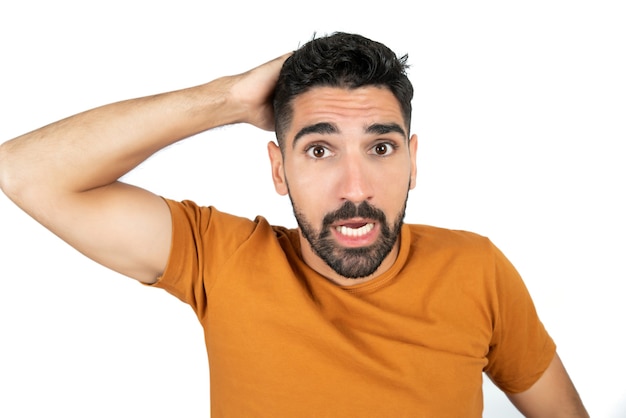 Portrait of young man looking worried about something against white background in studio.