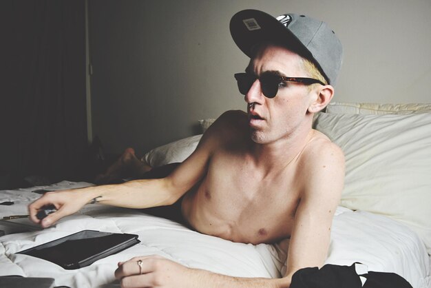 Photo portrait of young man lying in bed with tablet