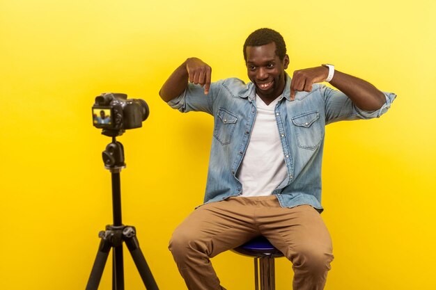 Portrait of young man photographing against yellow background