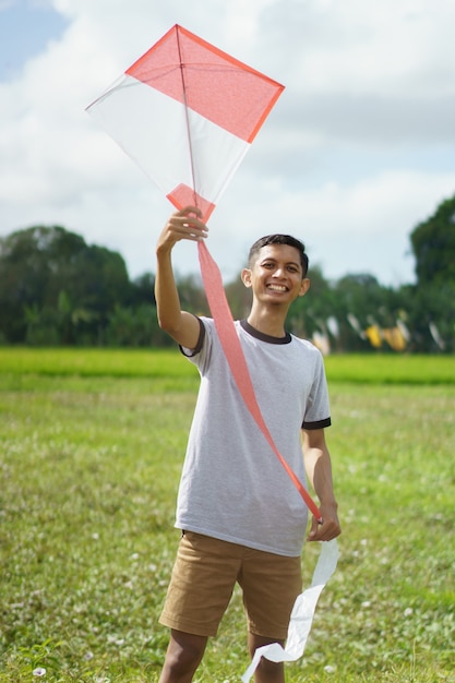 Portrait young man playing kite in the field