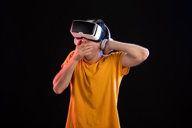 Portrait of young man playing vr in headphones on dark wall