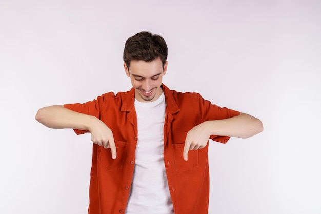 Portrait of young man pointing fingers at copy space isolated on white studio background