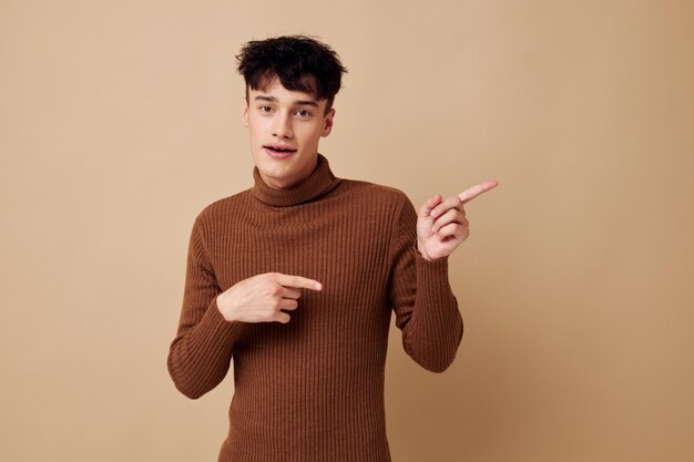 茶色のセーターの自信を持ってファッションでポーズをとっている若い男の肖像ライフスタイルは変わりません。高品質の写真
