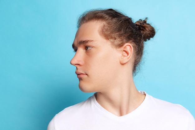 Foto ritratto di giovane uomo in posa distogliendo lo sguardo isolato su sfondo blu per studio