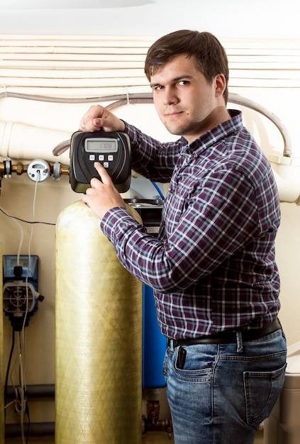 Portrait of young man pressing button on industrial equipment control panel