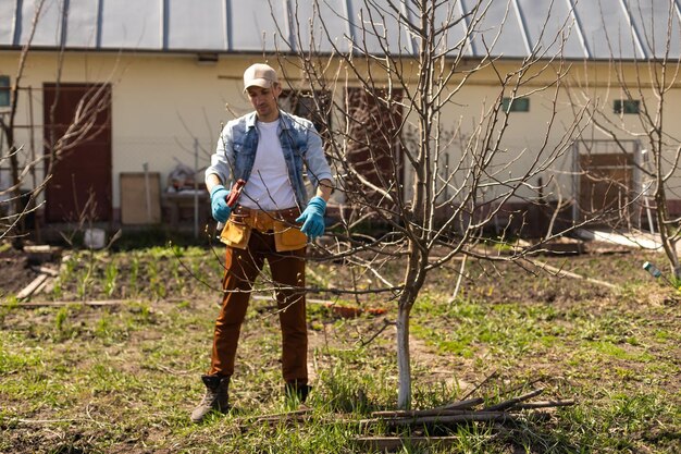 Portrait of young man pruning branch.