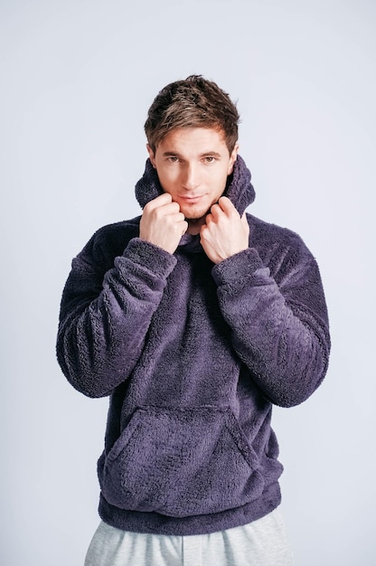 Portrait of a young man in purple sweatshirt with hood on a white background