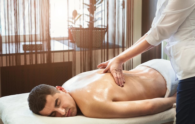 Portrait of young man receiving back massage in spa center