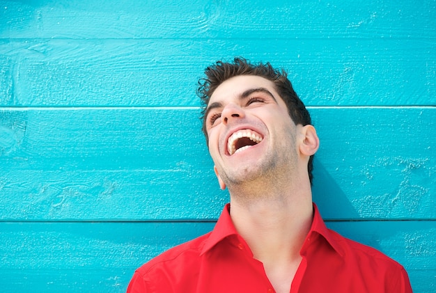 Foto ritratto di un giovane uomo in camicia rossa ridendo