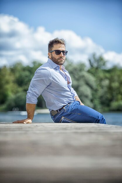 Portrait of young man relaxing on jetty by lake