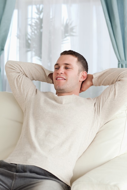 Портрет молодого человека, расслабляющий на диване в его гостиной