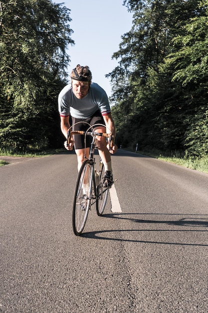 Portrait of young man riding bicycle on road during sunny day