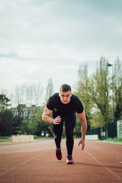 Foto ritratto di un giovane che corre su una pista sportiva contro il cielo