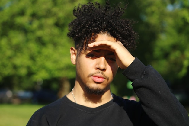 Portrait of young man shielding eyes