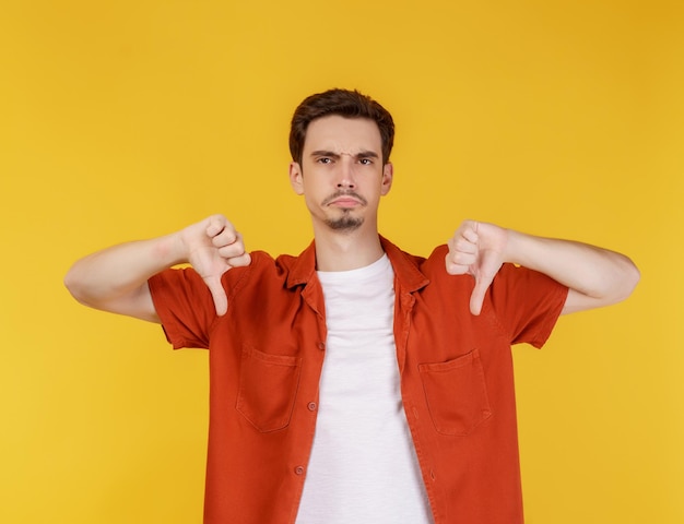 Portrait of young man shows sign of dislike looks with negative expression and disapproval on isolated background