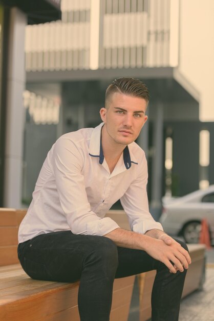 Photo portrait of young man sitting against building