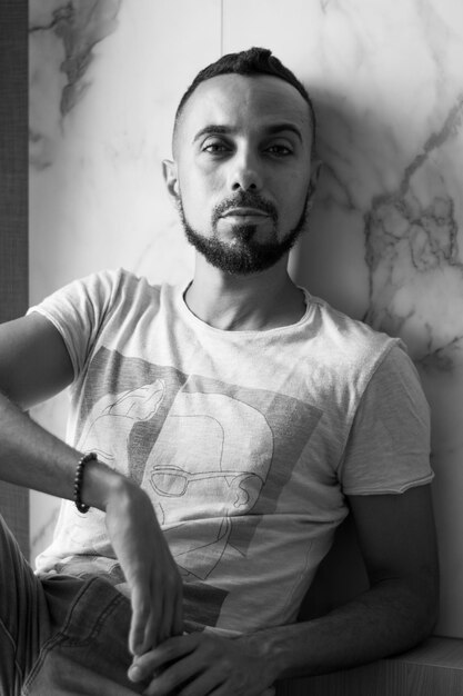 Photo portrait of young man sitting against wall