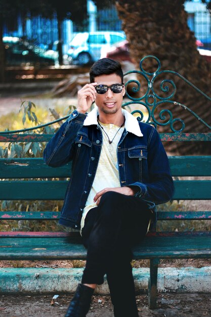 Photo portrait of young man sitting on bench